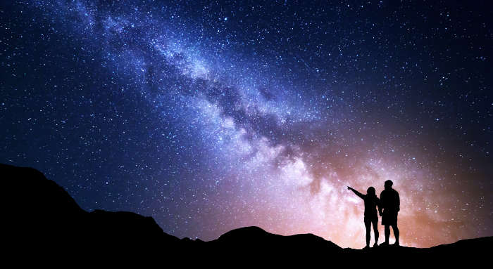 Two people looking and pointing at starry night sky