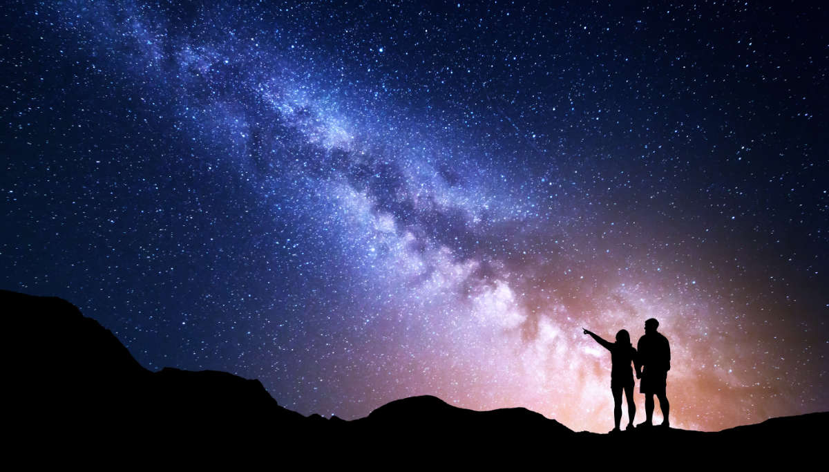 Two people looking at starry night sky